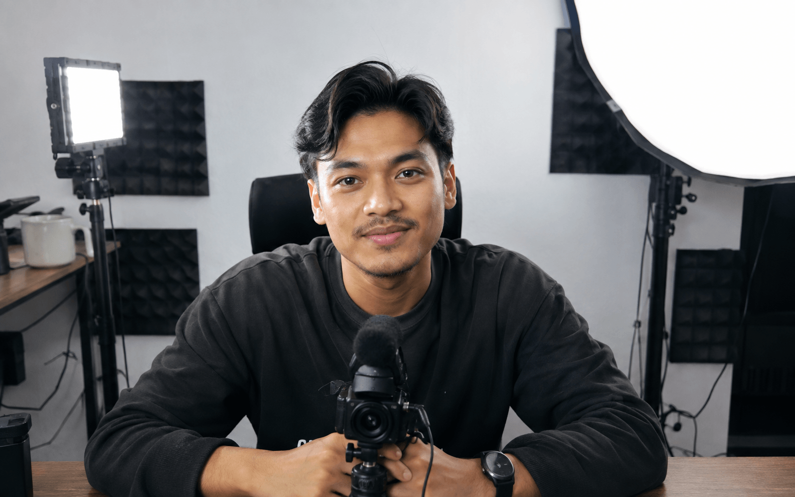 A creator at a desk in a small home studio, facing their camera