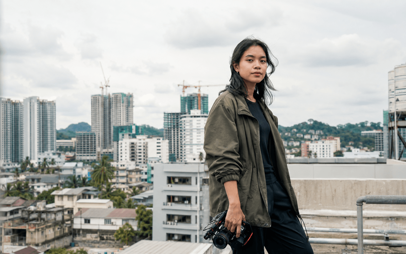 A filmmaker on a city rooftop holding a camera rig